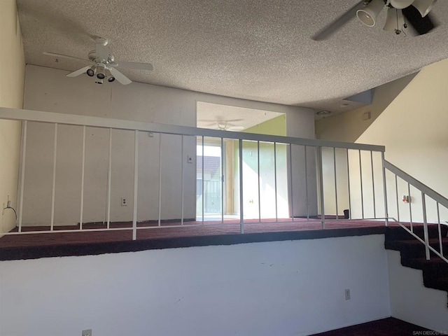 stairs with ceiling fan and a textured ceiling