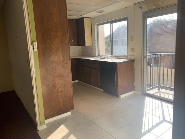 kitchen featuring sink, black dishwasher, and light tile patterned flooring