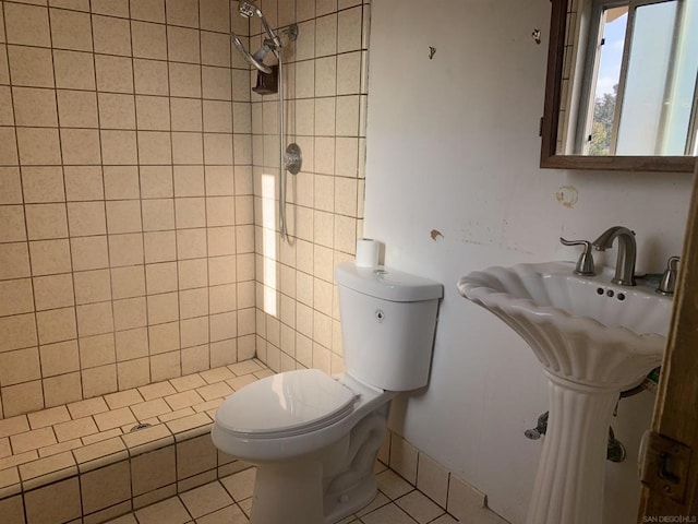 bathroom featuring toilet, a tile shower, and tile patterned flooring