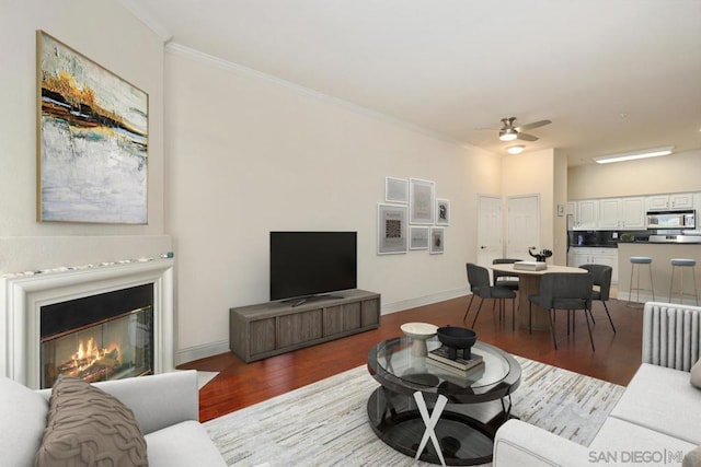 living room with wood-type flooring, ornamental molding, and ceiling fan