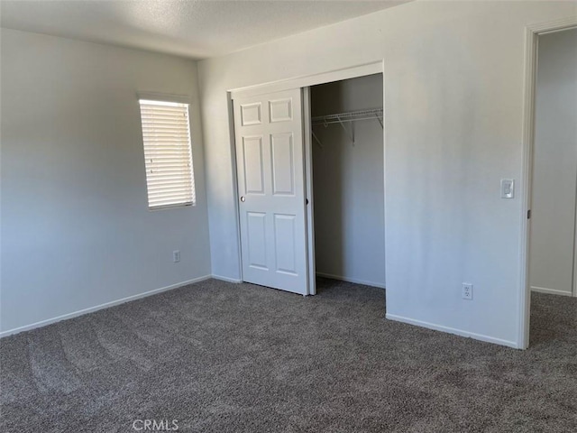 unfurnished bedroom with a closet and dark colored carpet