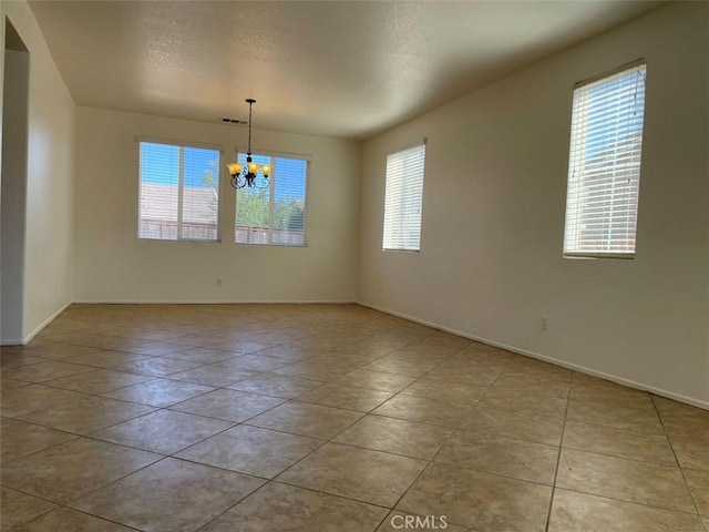 spare room featuring light tile patterned floors, a notable chandelier, and a textured ceiling