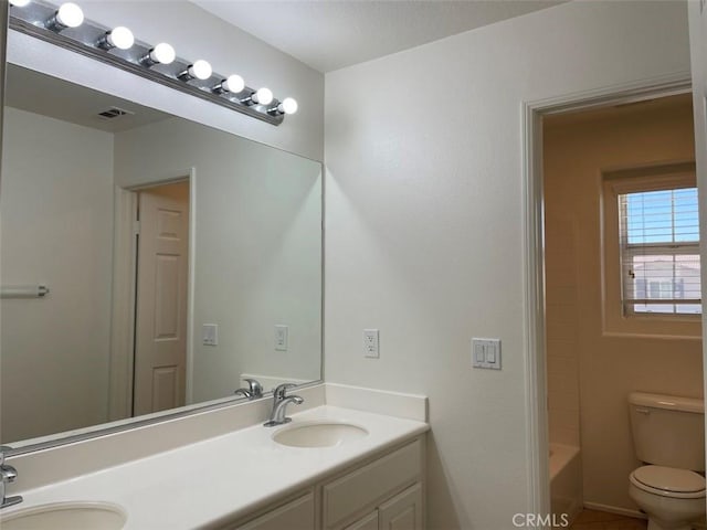 bathroom with toilet, vanity, and tile patterned flooring