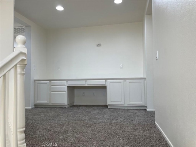 unfurnished office featuring built in desk and dark carpet