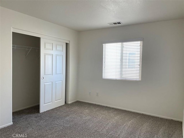 unfurnished bedroom featuring a closet and dark colored carpet