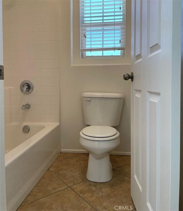 bathroom featuring toilet, tiled shower / bath, and tile patterned flooring