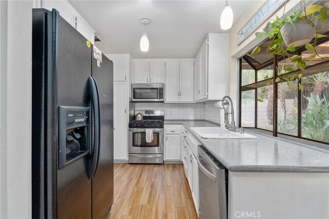 kitchen with hanging light fixtures, appliances with stainless steel finishes, sink, and white cabinetry