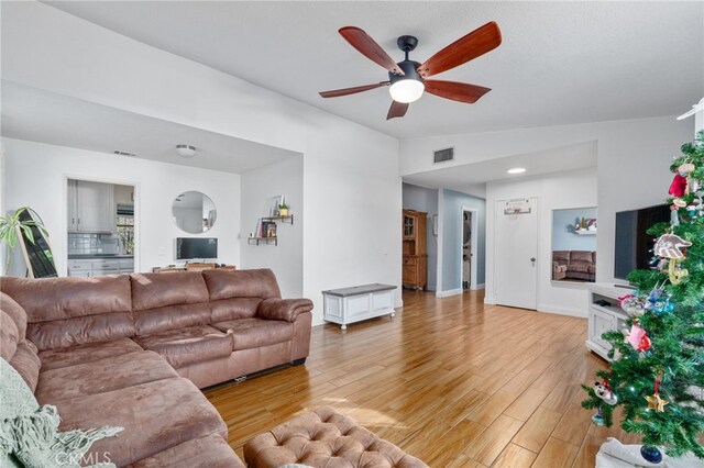 living room featuring ceiling fan, lofted ceiling, and light hardwood / wood-style floors