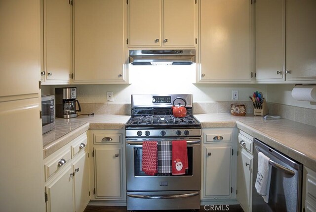 kitchen with stainless steel appliances, tile countertops, and cream cabinets