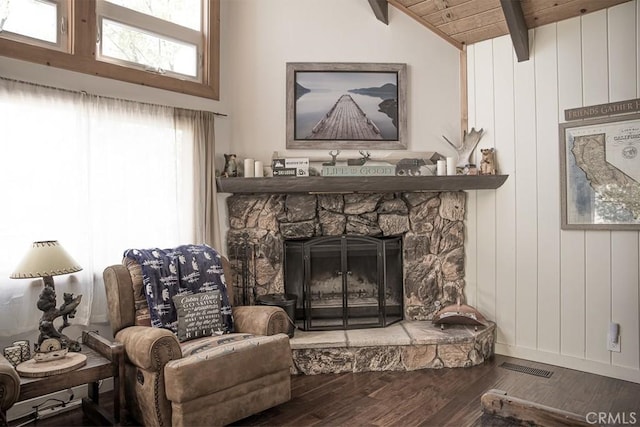 living area with wooden ceiling, vaulted ceiling with beams, wood-type flooring, and a stone fireplace