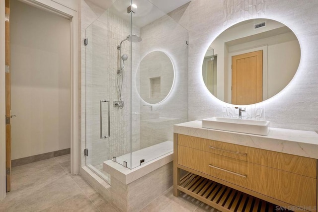 bathroom featuring tile patterned floors, vanity, a shower with door, and decorative backsplash