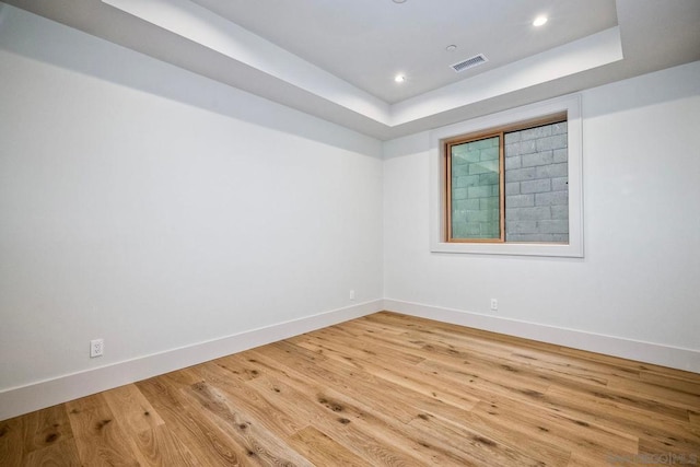 empty room featuring hardwood / wood-style floors and a tray ceiling