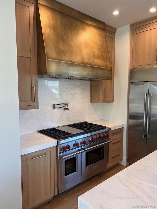 kitchen with tasteful backsplash, hardwood / wood-style flooring, custom range hood, and high quality appliances