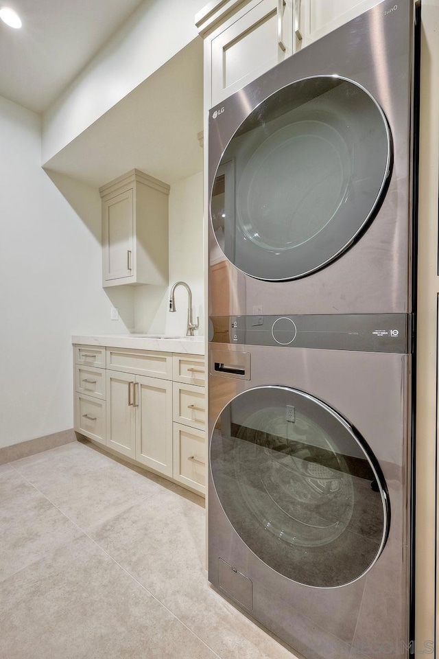 washroom with cabinets, stacked washer and dryer, sink, and light tile patterned floors