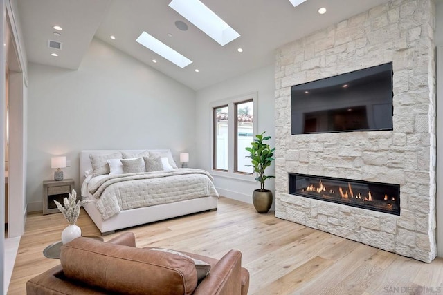 bedroom featuring a fireplace, light hardwood / wood-style flooring, and high vaulted ceiling