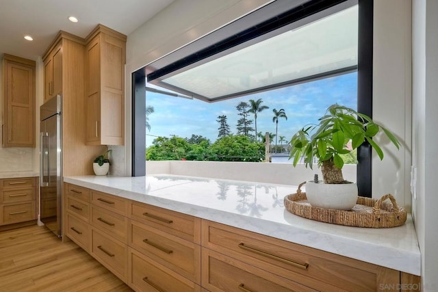 kitchen with high end refrigerator, light hardwood / wood-style floors, and backsplash