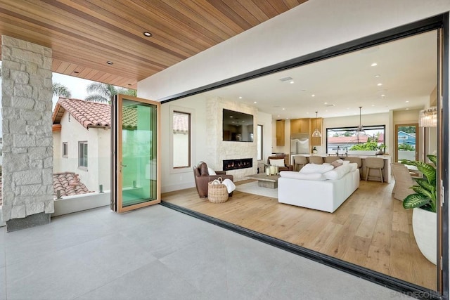 living room featuring a large fireplace and wood ceiling