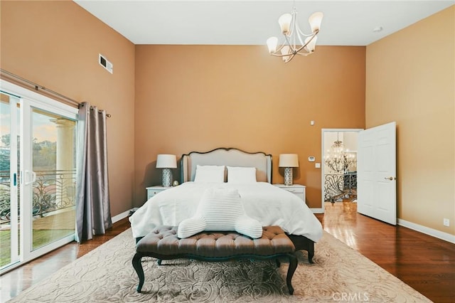 bedroom with access to outside, an inviting chandelier, and hardwood / wood-style flooring