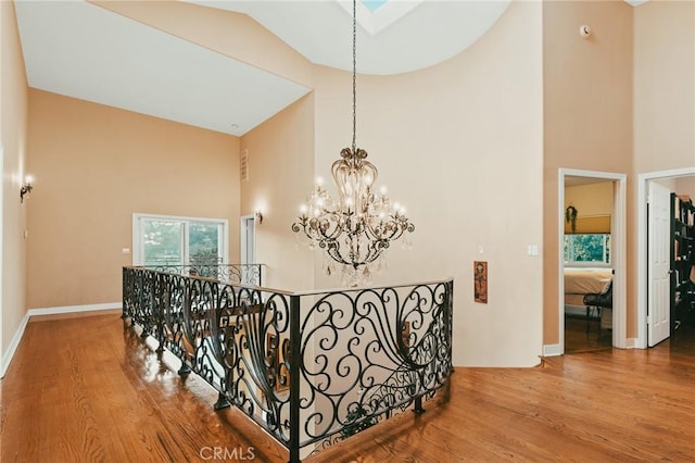 hallway featuring an inviting chandelier, wood-type flooring, and high vaulted ceiling