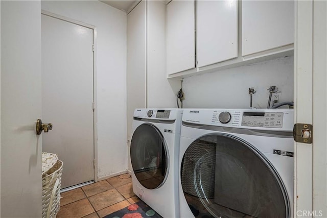 clothes washing area featuring cabinets, light tile patterned flooring, and washer and clothes dryer