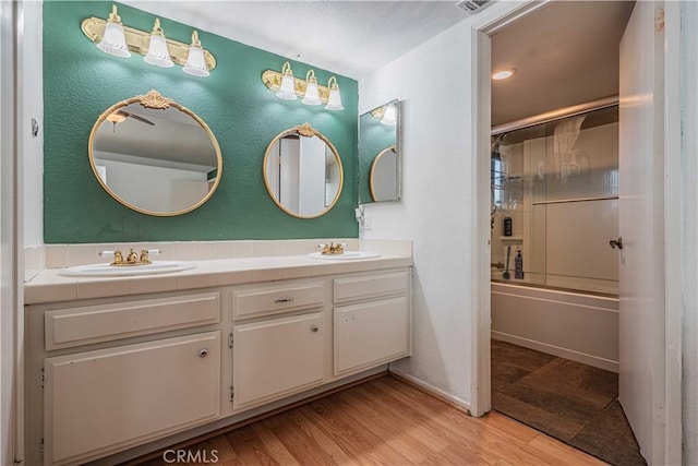 bathroom featuring hardwood / wood-style flooring, enclosed tub / shower combo, and vanity