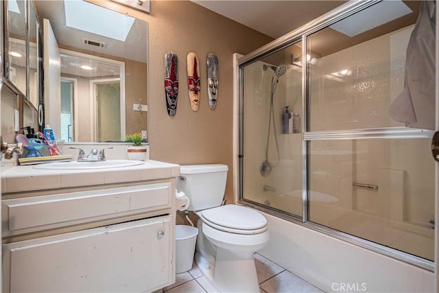 full bathroom featuring enclosed tub / shower combo, tile patterned flooring, vanity, a skylight, and toilet