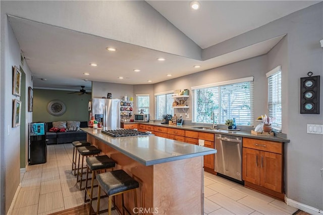 kitchen with a center island, a kitchen bar, stainless steel appliances, sink, and vaulted ceiling