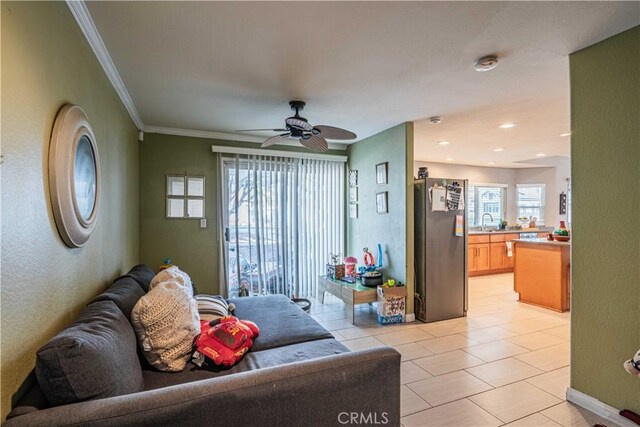 tiled living room with ceiling fan and crown molding