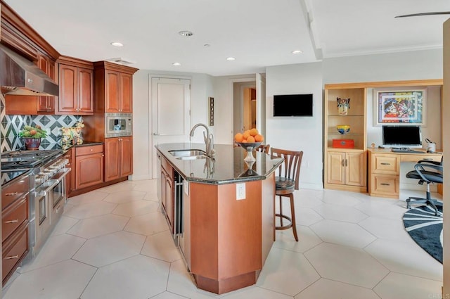 kitchen featuring decorative backsplash, sink, a kitchen breakfast bar, a kitchen island with sink, and stainless steel microwave