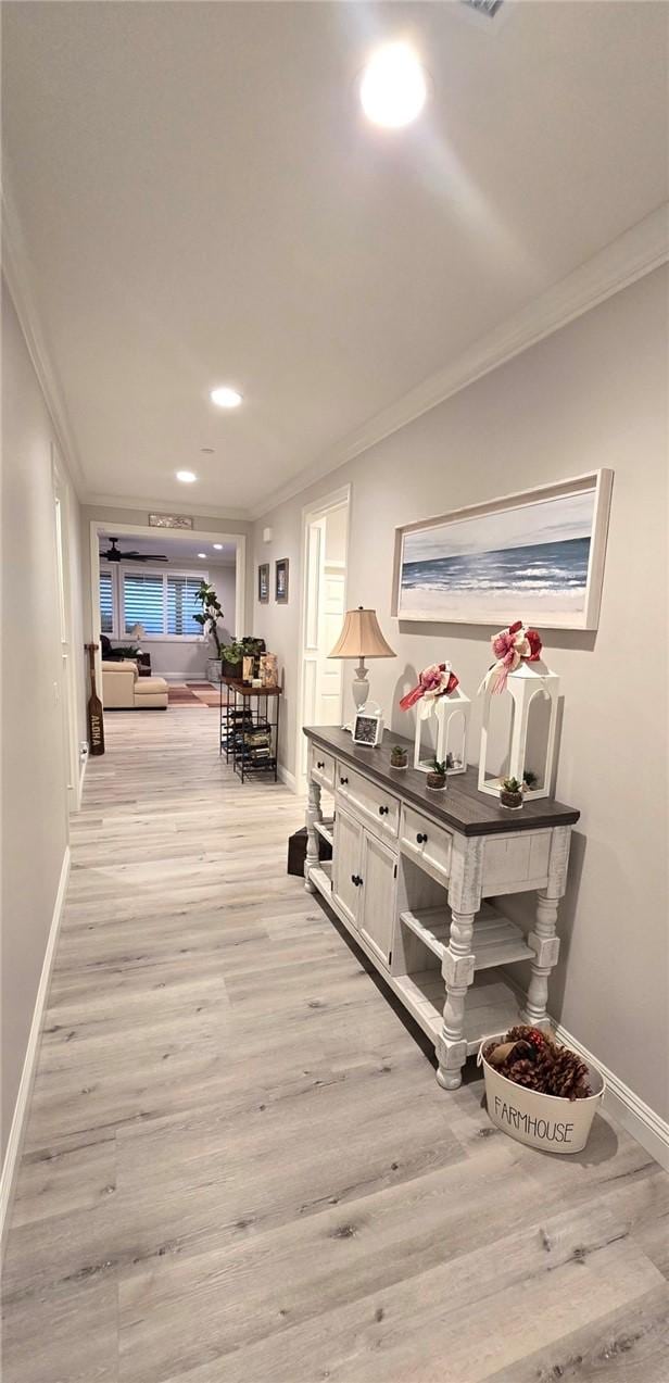 hallway featuring ornamental molding and light hardwood / wood-style floors