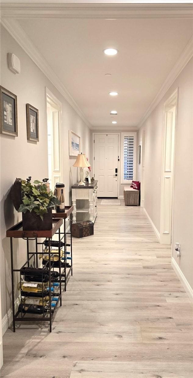 hallway with light wood-type flooring and crown molding