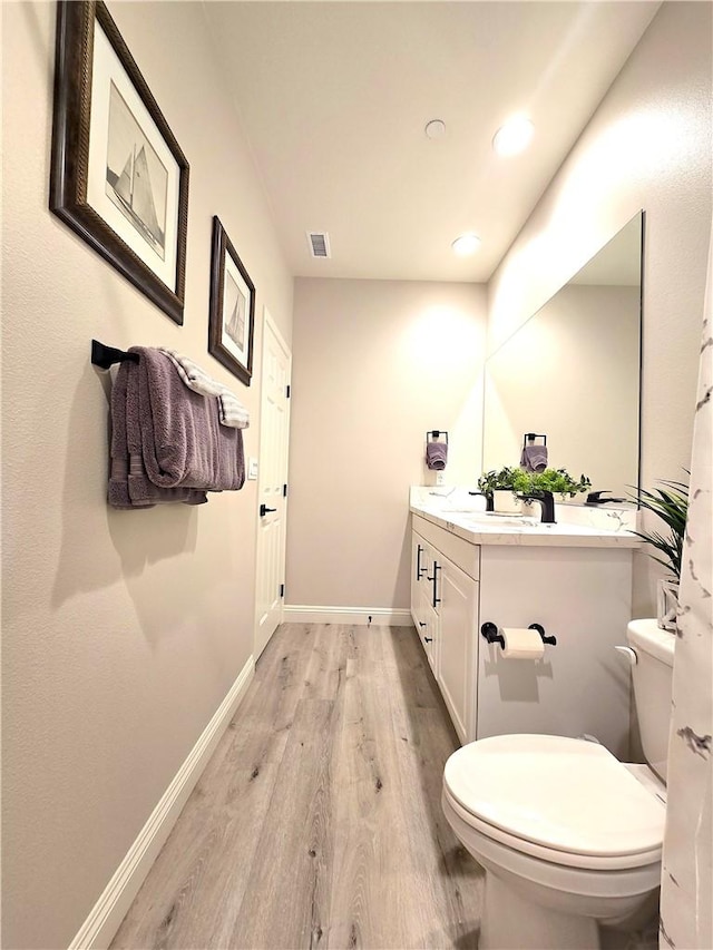 bathroom featuring toilet, hardwood / wood-style floors, and vanity