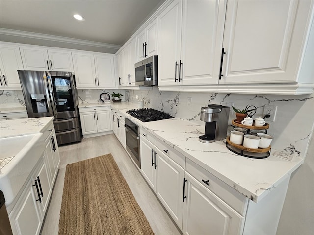 kitchen with light wood-type flooring, appliances with stainless steel finishes, decorative backsplash, and white cabinets