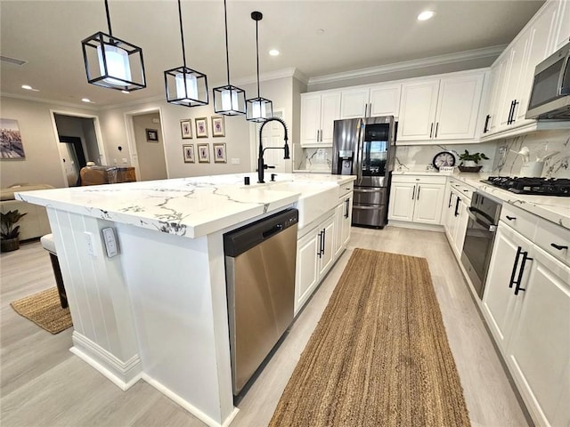 kitchen with appliances with stainless steel finishes, decorative backsplash, a kitchen island with sink, pendant lighting, and white cabinets