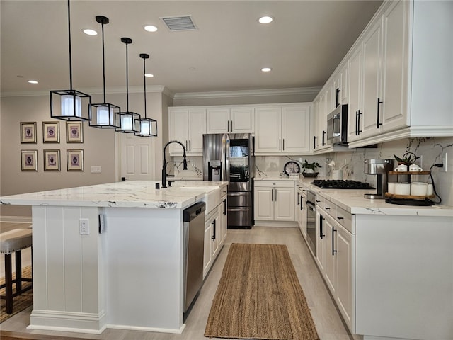 kitchen with white cabinets, a kitchen island with sink, and appliances with stainless steel finishes