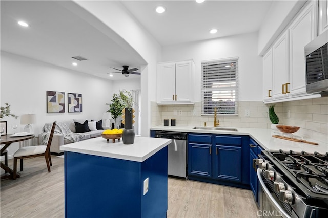 kitchen with sink, white cabinets, blue cabinetry, and stainless steel appliances