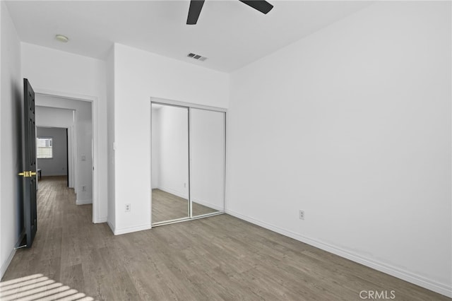 unfurnished bedroom featuring ceiling fan, a closet, and hardwood / wood-style floors