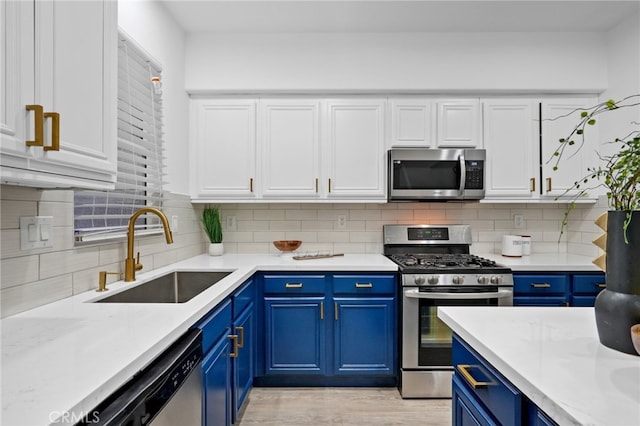 kitchen featuring decorative backsplash, sink, white cabinetry, blue cabinetry, and stainless steel appliances