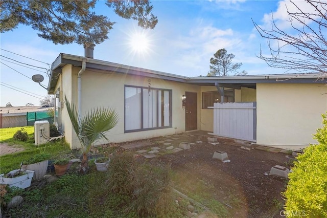 rear view of property with fence and stucco siding