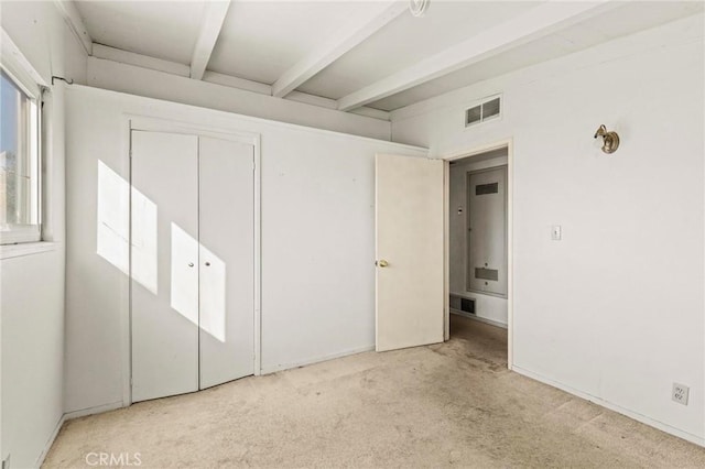 unfurnished bedroom featuring a closet, beam ceiling, carpet flooring, and visible vents