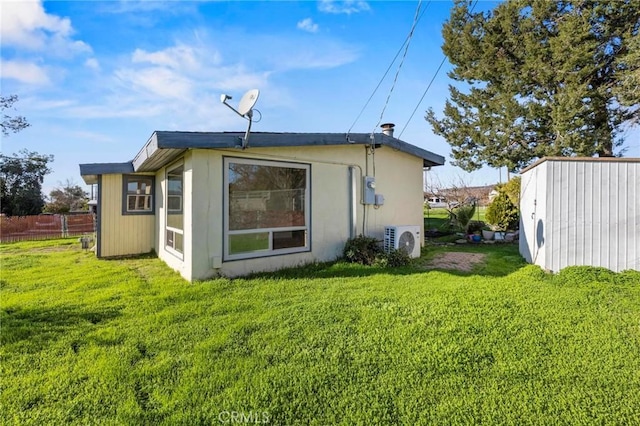 rear view of property featuring a yard, ac unit, and fence