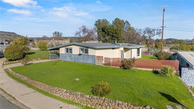 view of home's exterior featuring a carport, a lawn, and fence