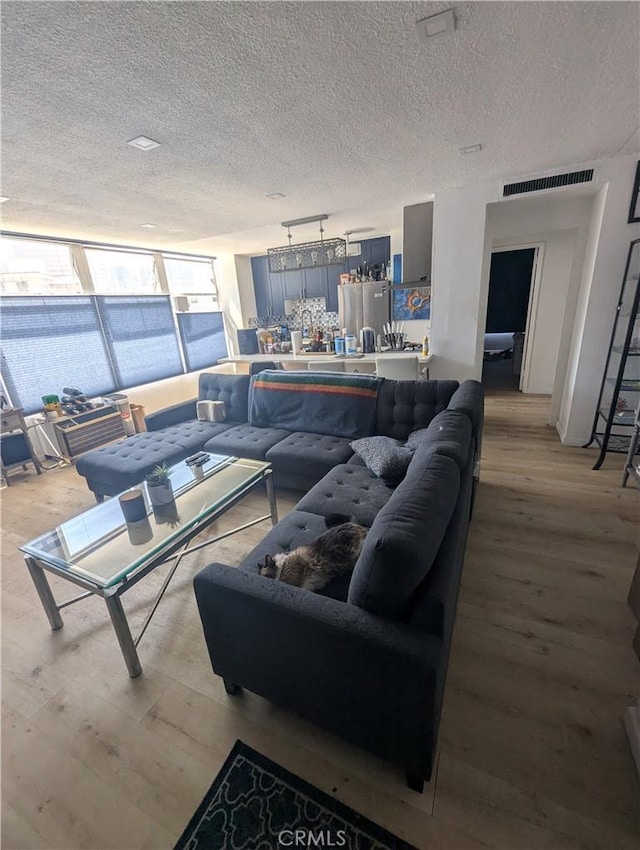 living room featuring a textured ceiling, track lighting, and light hardwood / wood-style flooring