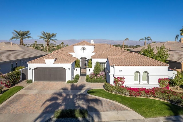 mediterranean / spanish home featuring a garage and a front lawn