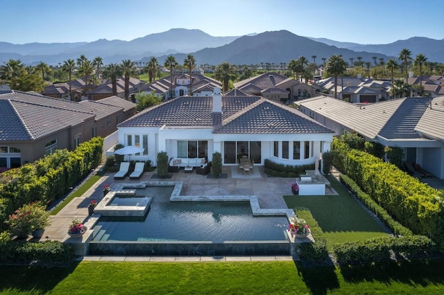 back of house featuring an outdoor hangout area, a patio area, a mountain view, and a yard