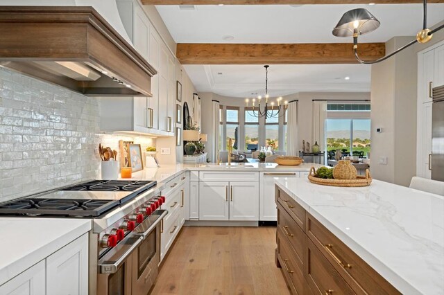 kitchen with white cabinets, custom exhaust hood, decorative light fixtures, range with two ovens, and a chandelier