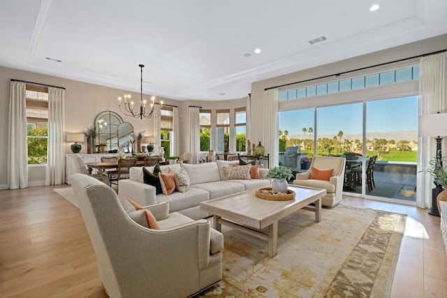 living room with light hardwood / wood-style floors, a wealth of natural light, and a raised ceiling