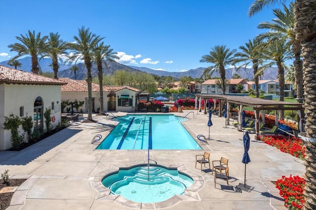 view of swimming pool featuring a patio, a mountain view, and a community hot tub