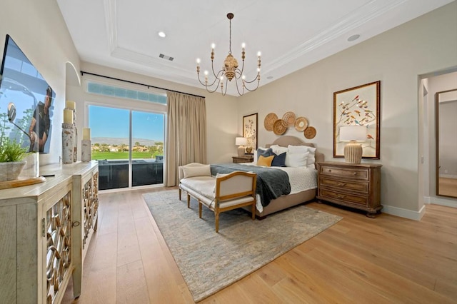 bedroom with an inviting chandelier, light hardwood / wood-style flooring, a raised ceiling, and access to outside