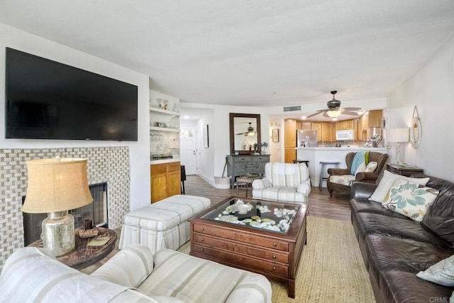 living room with ceiling fan, wood-type flooring, and a fireplace